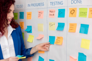 Mulher apresentando quadro com termos do Scrum, como Product Owner e Sprint, em um ambiente de equipe ágil